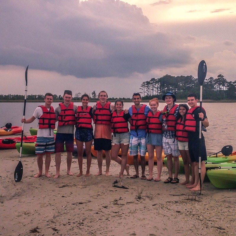 a group of people standing on top of a sandy beach